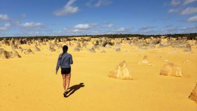 Girl walking in Pinnacles Desert with rock formations in the sand