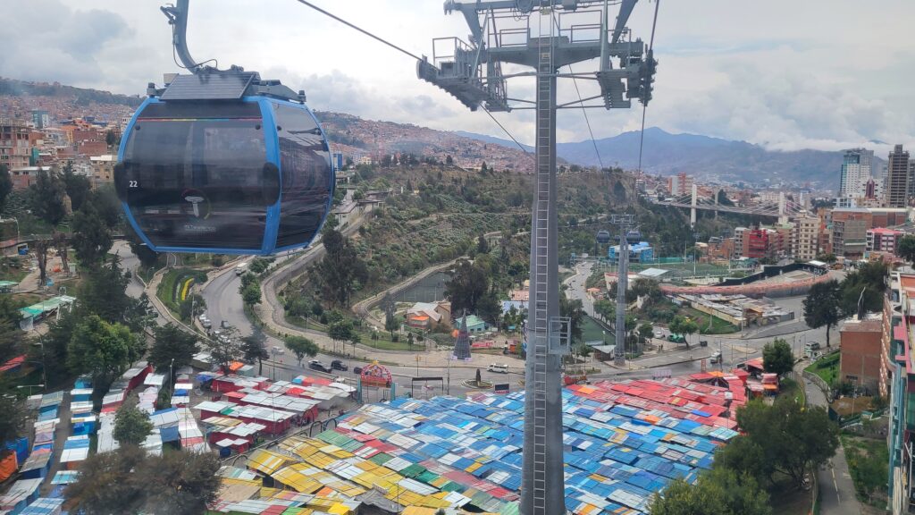 LInea Celeste cable car over La Paz below; colorful market stalls and mountains in distance