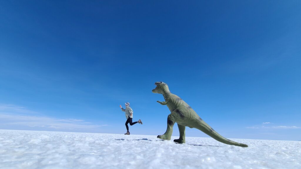 Illusion photo in Uyuni salt flats, girl running from dinosaur