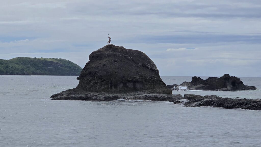An authentic cultural sight in the Yasawa Islands: a traditional warrior standing on a rock and welcoming guests
